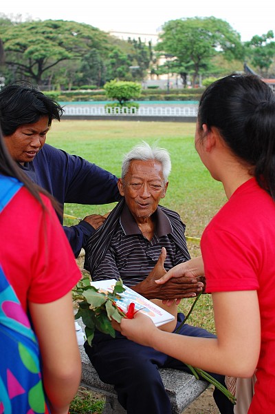 82-year-old Mang Noel reacts upon receiving a flower and encouragement cards from a group of Adventist youth celebrating Global Youth Day through acts of compassion in a Manila park, March 15. [photo by RJ Almocera]