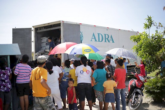 Residents of Casiguran look on as emergency shelter kits are unloaded from an ADRA truck. The Adventist Development and Relief Agency in the Philippines was first to respond two days after typhoon Koppu hit parts of north Philippines on October 18. [photograph by ADRA Philippines]