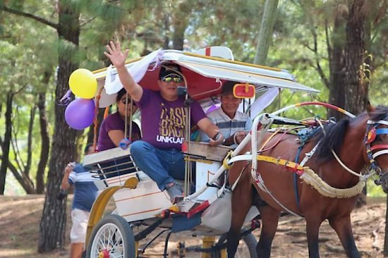 Mt. Klabat University (UNKLAB) president, Dr. Tommy Mambu, waves from a small horse-drawn cart, at the opening parade on October 15 during the university's 50th anniversary celebration. The event lasted for three days. [photo contributed by J. Rondonuwu]